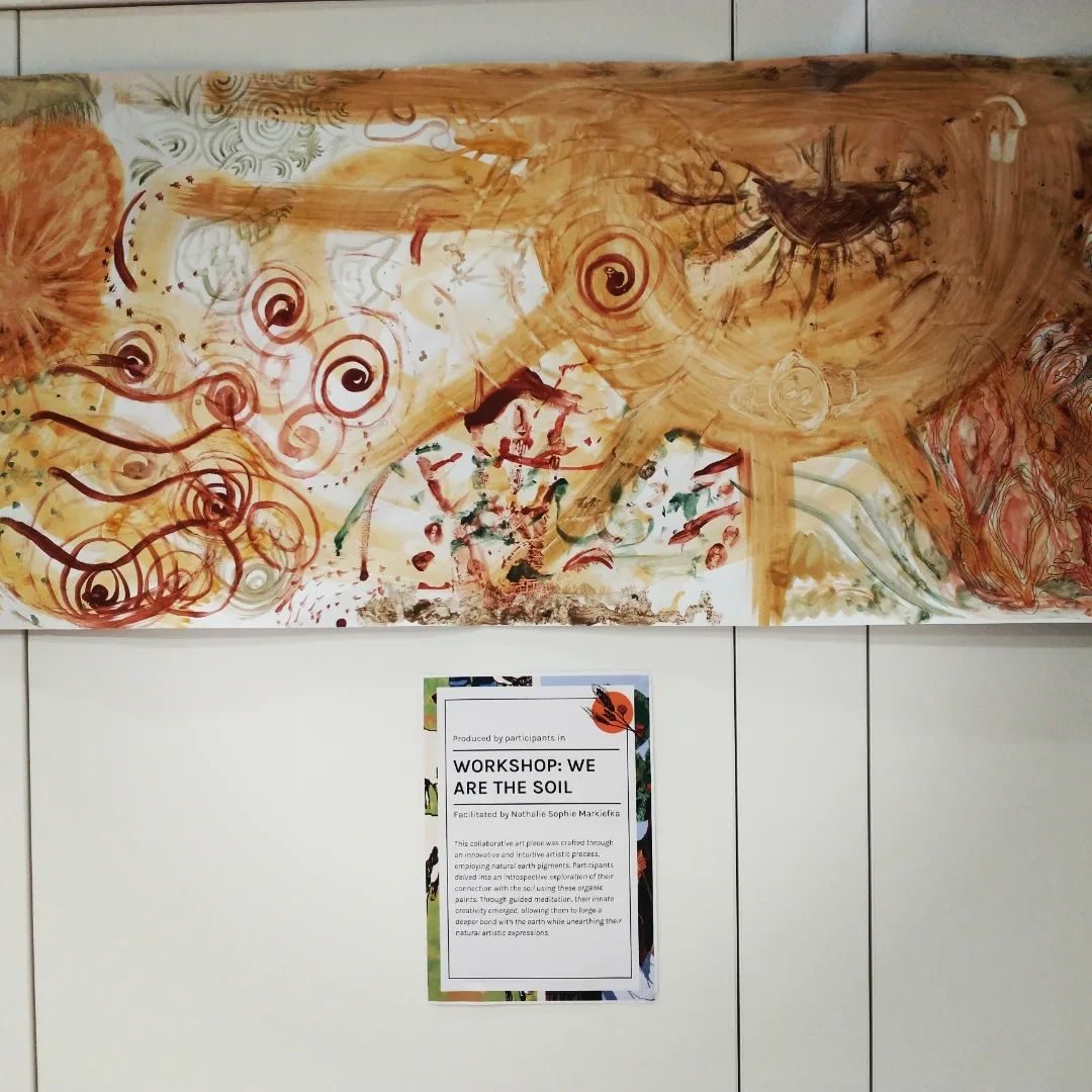 The finished collaborative earth-pigment painting on display, with the workshop's exhibit label